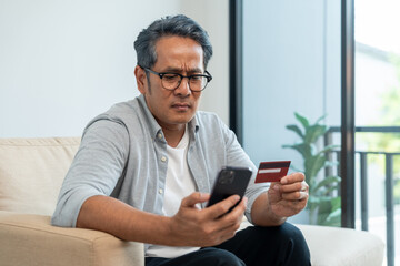 Mature asian old man holding credit card input number in smartphone for payment online. Pay with credit card on cell phone lifestyle technology financial for senior people