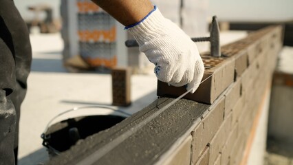 Construction worker building a brick wall using string as guide