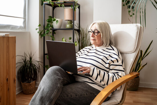 Senior woman using a laptop at home in a modern living room
