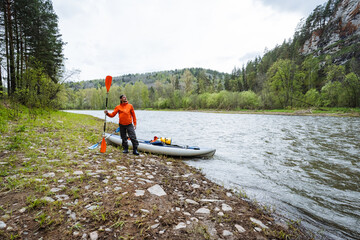 A dedicated kayaker prepares for an exhilarating trip in a vibrant riverside landscape filled with...