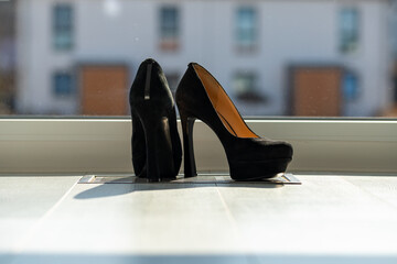 Black ladies pumps on the floor in front of a window