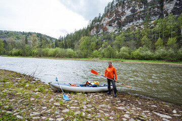 An Adventurous Kayaker Enthusiastically Preparing for an Exciting Scenic River Expedition, All Set...