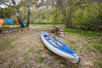 Experience a Serene Camping Scene featuring a Kayak gently resting by the Waters Edge, surrounded by a vibrant expanse of Lush Greenery and a peaceful atmosphere perfect for relaxation and adventure