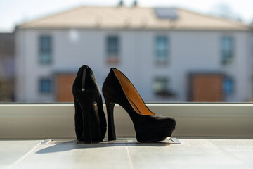 Black ladies pumps on the floor in front of a window