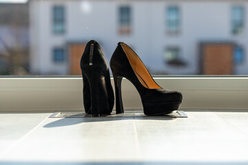 Black ladies pumps on the floor in front of a window