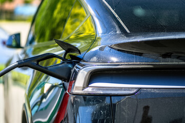 Detail of a connected charging station for a electric car. Rear light of the car with a charging connector.