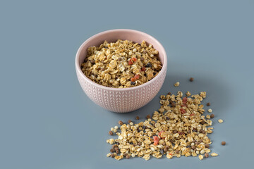 Muesli with dried fruit close-up , high-resolution .Side view of a ceramic bowl with granola on the grey background , place for text . 