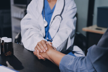 female doctor or woman medical staff holding hand, working hand in hand, giving encouragement to patient or relative of patient; concept of woman health care worker, doctor, therapist, medical worker