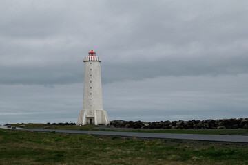 Lighthouse in Akranes, Iceland against a cloudy sky with rocky shoreline