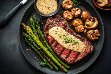 Delicious steak with creamy mushroom sauce served with asparagus and saut&eacute;ed mushrooms