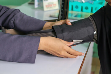 Close up of muslim woman patient having their blood pressure checked with a cuff. Medical exam for...