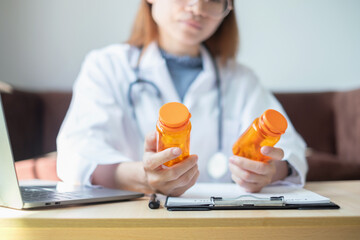 Female doctor holding a medicine bottle is checking the quality of medicine for any side effects the patient or not and recording patient information at the hospital. medical and health care concept