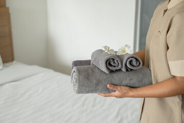 A hotel maid stacked towels on the bed and placed flowers on the towels in a hotel room