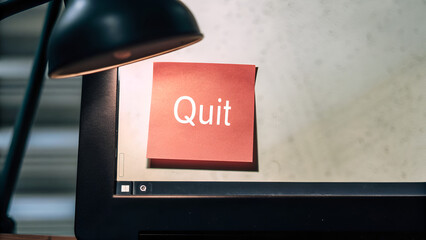 Quiet Quitting Job Burnout Employee Post-it note with the word "Quit" displayed on a computer screen beside a desk lamp.