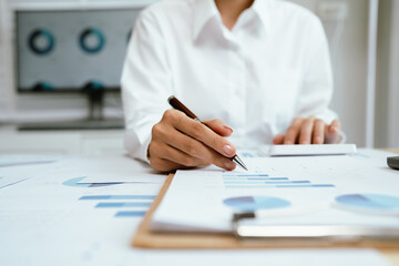 Close up of professional businessman sitting at desk in modern office, analyzing charts and financial documents, planning business growth and investment strategy.