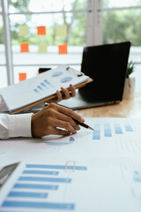 Close up of professional businessman sitting at desk in modern office, analyzing charts and financial documents, planning business growth and investment strategy.
