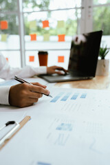 Close up of professional businessman sitting at desk in modern office, analyzing charts and...