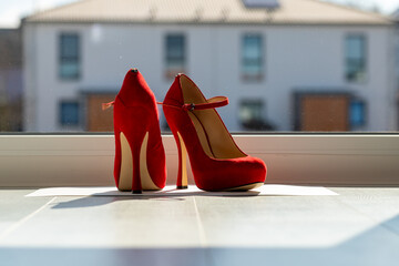 Red ladies pumps on the floor in front of a window
