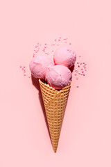 Strawberry pink ice cream scoops in waffle cone on pink background