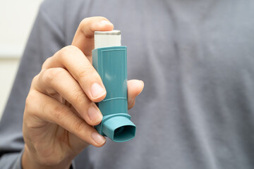 Asthma and chronic obstructive pulmonary disease COPD, Asian young man using metered dose inhaler...