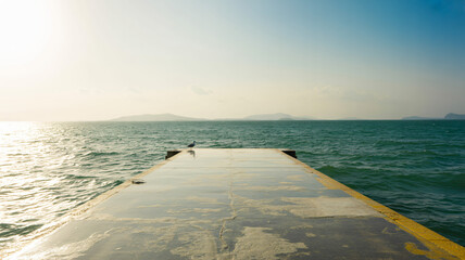Empty paved platform overlooking a vast expanse of tranquil sea bathed in natural sunlight