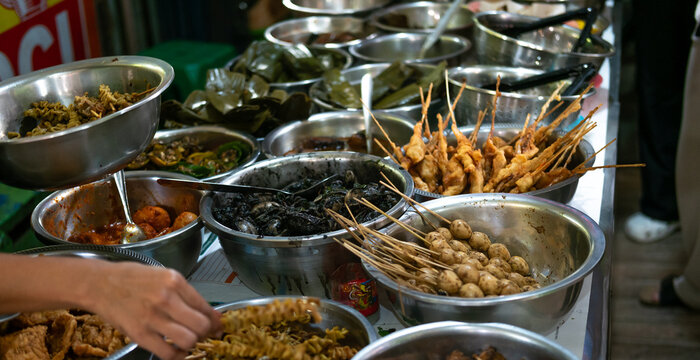 A vibrant array of Nasi Jamblang side dishes, often displayed buffet-style, offering diverse flavors and textures like blakutak cumi or various sambals, designed to complement the teak-leaf wrapped ri