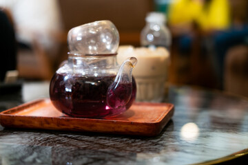  a glass teapot filled with a vibrant purple-red herbal tea, likely dragon fruit tea, on a wooden...