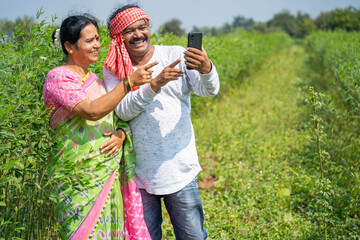 Obraz premium Happy Indian farmer couple at their farm using smartphone