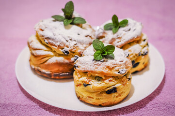 Close up of miniature panettones sprinkled with icing sugar and decorated with fresh mint leaves.
