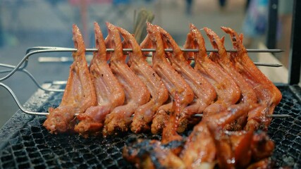 Sizzling chicken wings grilling over hot charcoal, releasing tantalizing smoky flavors and golden brown crispy exterior during outdoor summer cooking