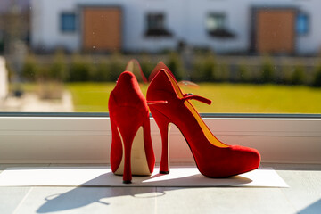 Red ladies pumps on the floor in front of a window