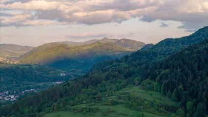 Obraz premium Aerial view of fields and landscape in the Pieniny Mountains in Poland during a May sunset, beautiful fresh spring greenery bathed in the light of the setting sun.