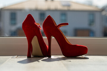 Red ladies pumps on the floor in front of a window