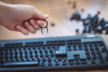 Hand holding a keycap puller above a mechanical keyboard with scattered keycaps on the table