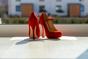 Red ladies pumps on the floor in front of a window