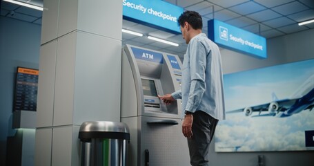 ATM Machine in Crowded Airport Terminal: Man Pressing Buttons on ATM Keypad, Entering PIN Code for...