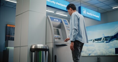 ATM Machine in Crowded Airport Terminal: Man Pressing Buttons on ATM Keypad, Entering PIN Code for Money Withdrawal Operation, Taking Cash. Cash Machine, Banking Services and Transactions. Medium Shot