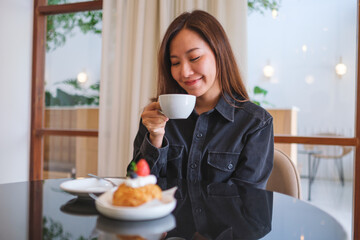 Portrait image of a woman holding and drinking coffee in cafe