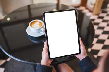 Mockup image of a woman holding digital tablet with blank white desktop screen in cafe