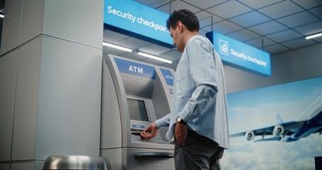Cash Machine in Crowded Airport Terminal: Man Pressing Buttons on ATM Keypad, Entering PIN Code for...