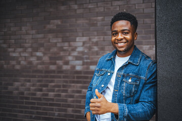 Smiling Man Giving Thumbs Up in Front of a Brick Wall Background