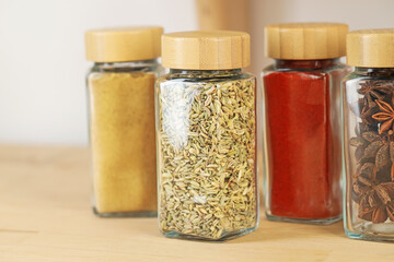 Many different aromatic spices in jars on wooden table indoors, closeup