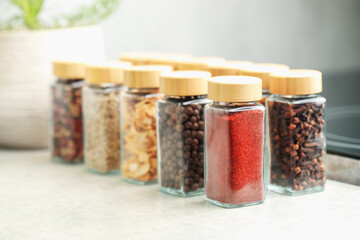 Many different aromatic spices in jars on table indoors, closeup