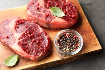 Pieces of raw beef meat and spices on gray table, closeup