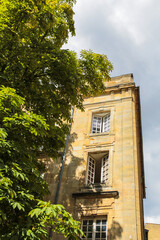 A building in Bordeaux France with a lot of windows and a tree in front of it