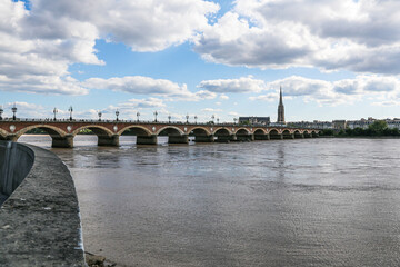 Fototapeta premium A Stone bridge in Bordeaux France spans a river Garonne with a city in the background