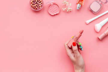 Flat lay of makeup cosmetic products and accessories in brown pink shades, top view. Powder, blush and lipstick