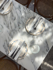 A restaurant table setting captured in natural daylight with light and shadow patterns