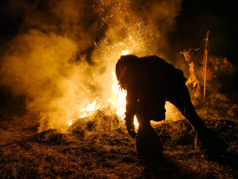 Silhouette of a Krampus figure tending a large bonfire, sparks flying. Krampus and St Nicholas, 5 December in Tarvisio, Friuli Venezia Giulia, Julian Alps, Italy.