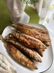 Fried smelt on a plate. grilled fish on the background of a flower succulent in a pot in the form of Nefertiti's head. Food background